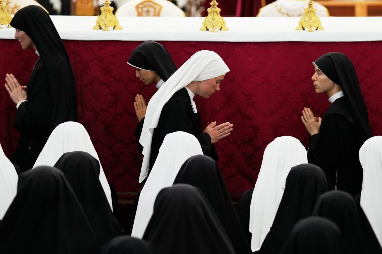 Nuns attend a consecration ceremony for four new bishops