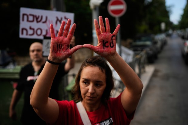 A woman holds up her hands, painted red to symbolize blood with the words in Hebrew "we will not forget" during a protest marking 1,000 days since the Oct. 7 2003 Hamas-led attack on Israel, outside the prime minister residence in Jerusalem, Thursday, July 2, 2026. (AP Photo/Ohad Zwigenberg)