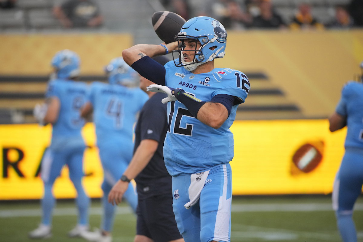 A football player in a light blue uniform with the number 12 prepares to throw the ball during a game.