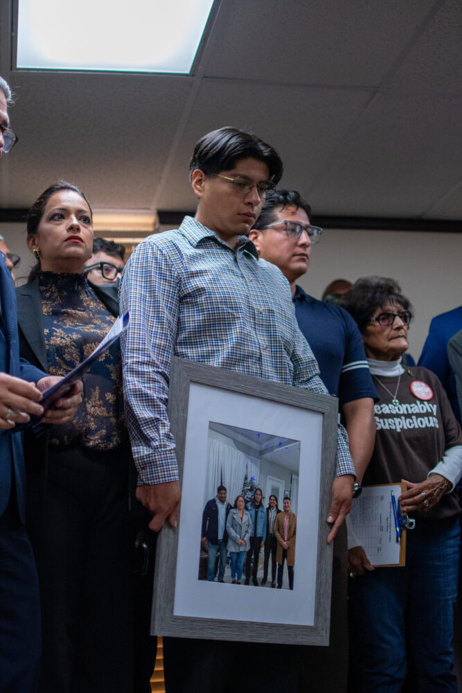 Lorenzo Salgado Araujo's middle son holds a photo of his father who was shot and killed by ICE. July 8, 2026.
