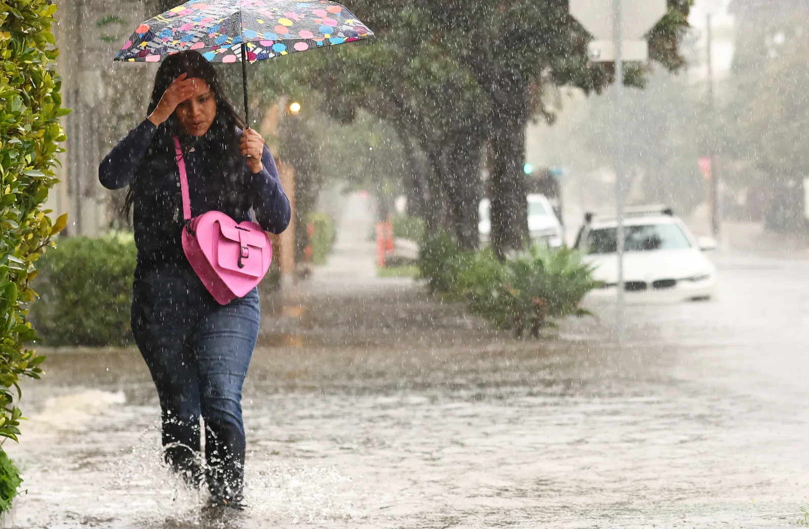 A person walks along a flooded street as a powerful long-duration atmospheric river storm hits California on February 4, 2024.
