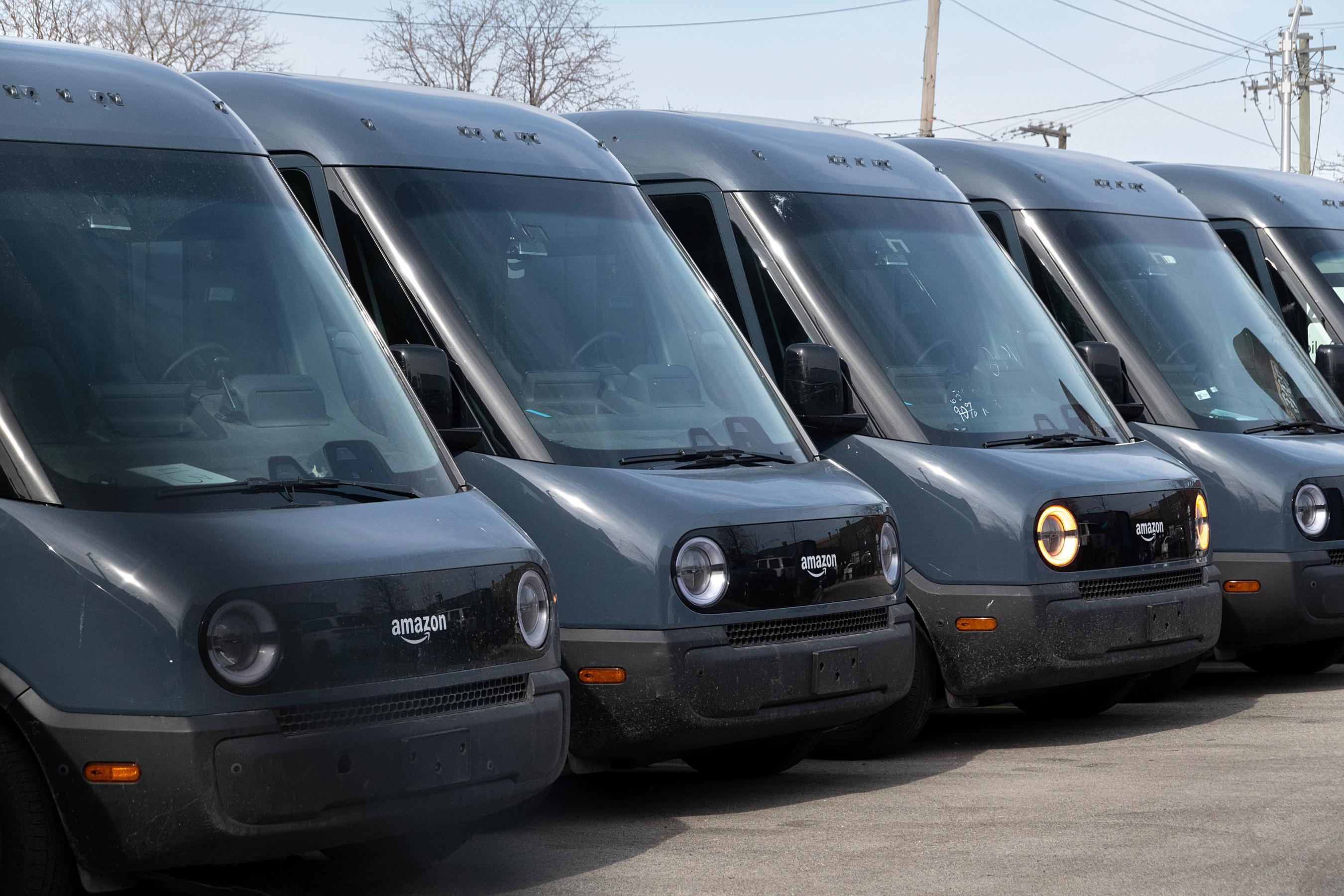 A line of parked dark blue Rivian Amazon branded delivery vans.