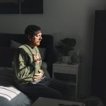 A mature man meditates in the last sun rays coming into his bedroom - stock photo
