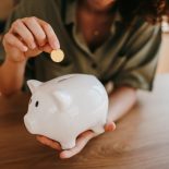 Woman saving money inserting coin in piggy bank - stock photo