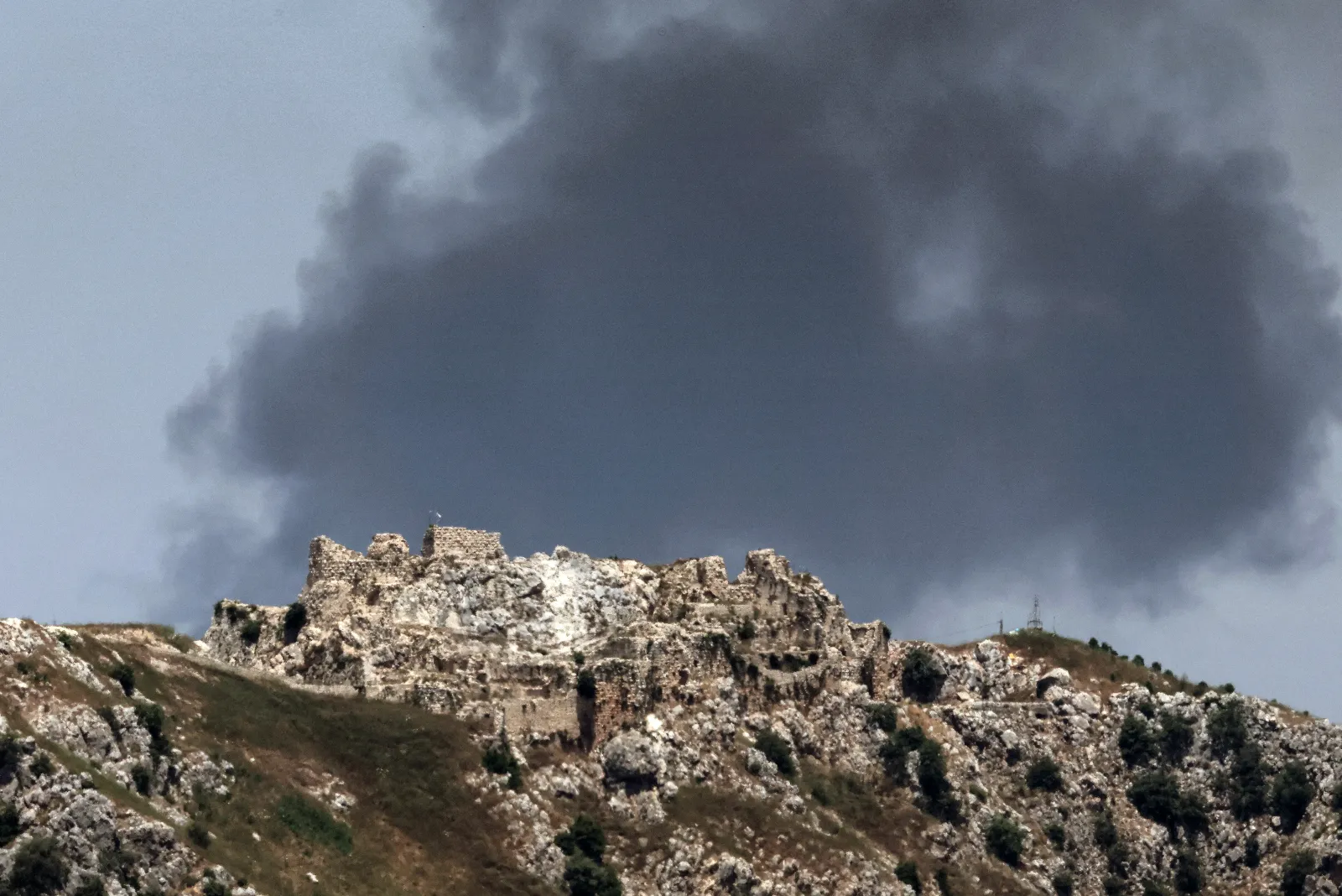 This picture taken from a position in the Upper Galilee in northern Israel on June 17, 2026, shows smoke billowing in the distance behind the medieval Beaufort Castle in southern Lebanon.