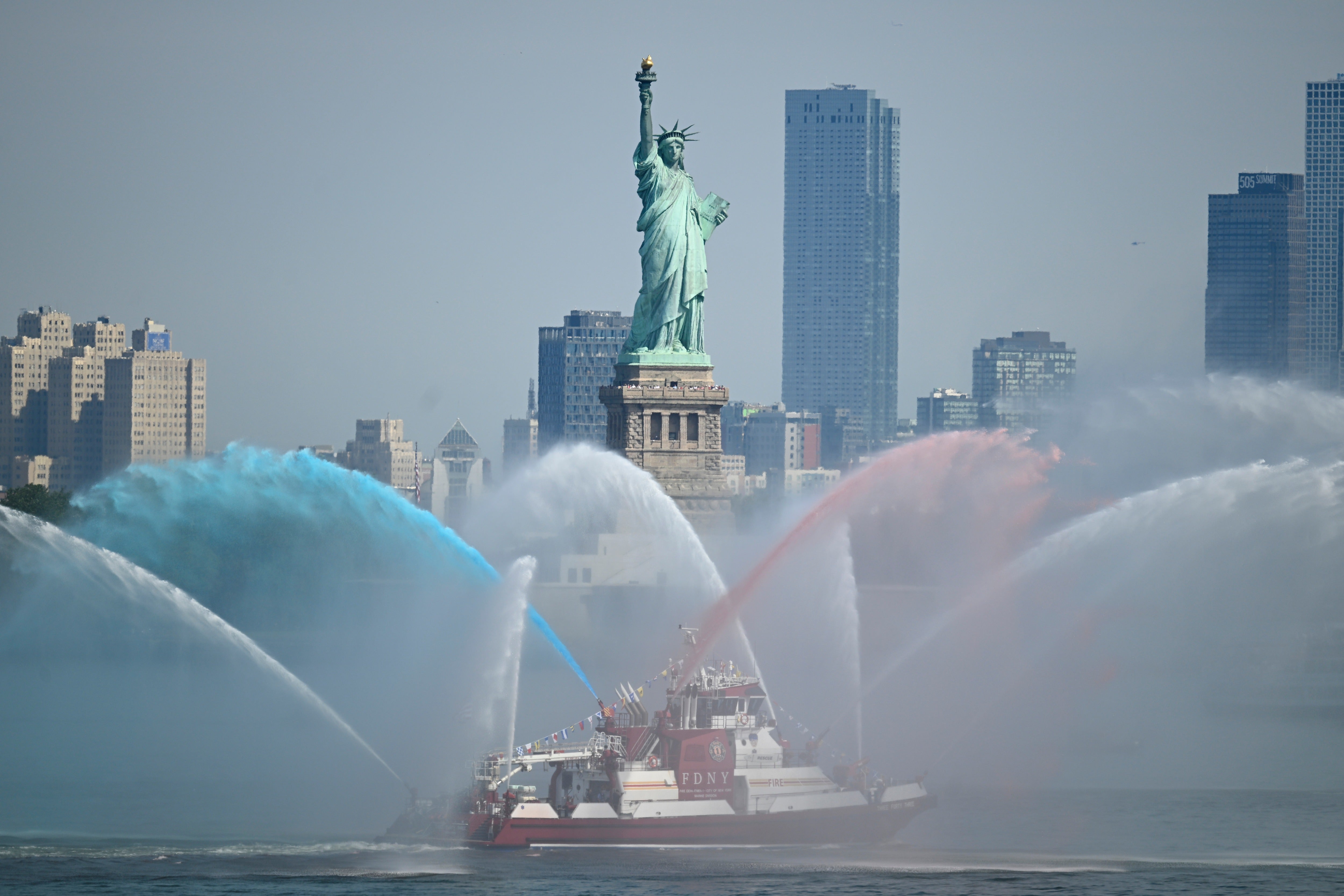 An FDNY boat sprays its hoses in tribute in front of the Statue of Liberty ahead of an international parade of tall sailing ships in New York Harbor