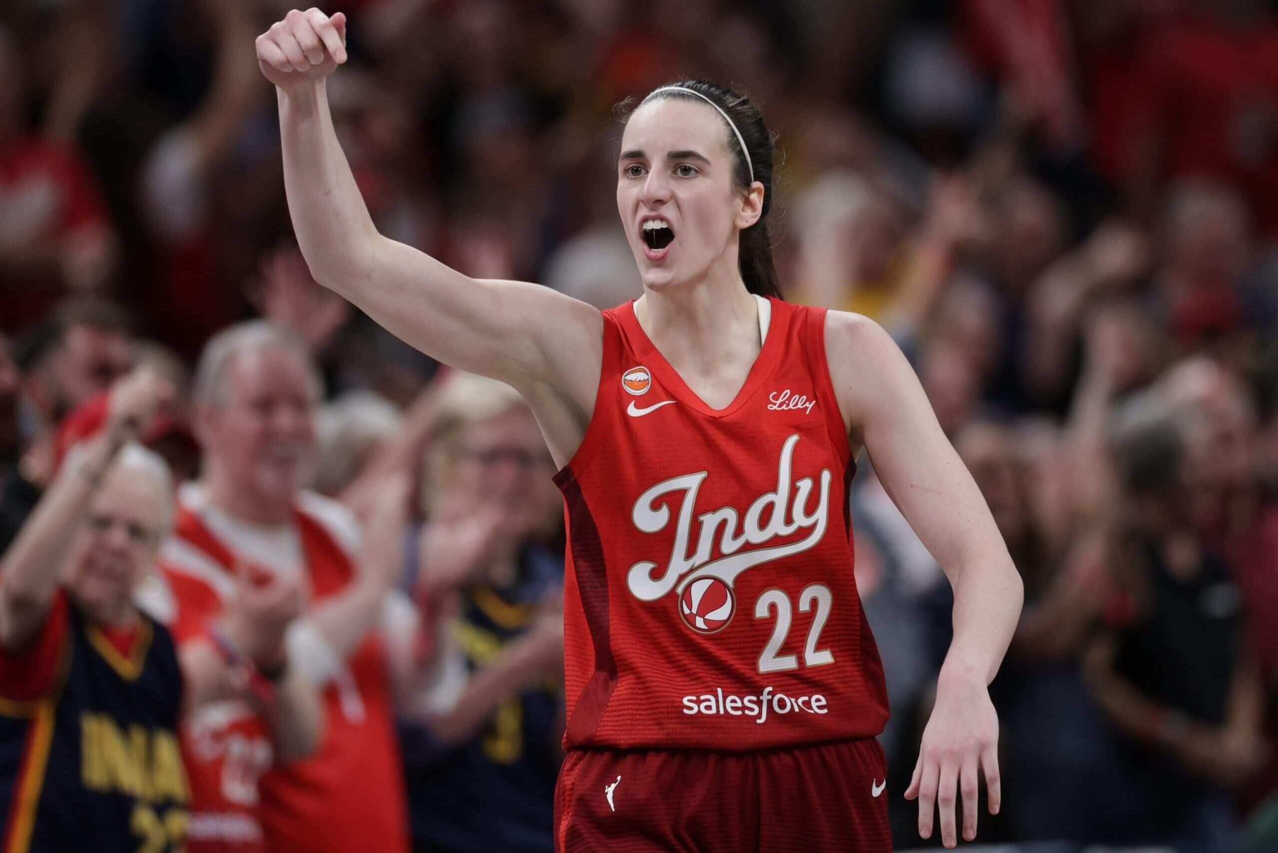 Caitlin Clark gestures with her raised right hand.