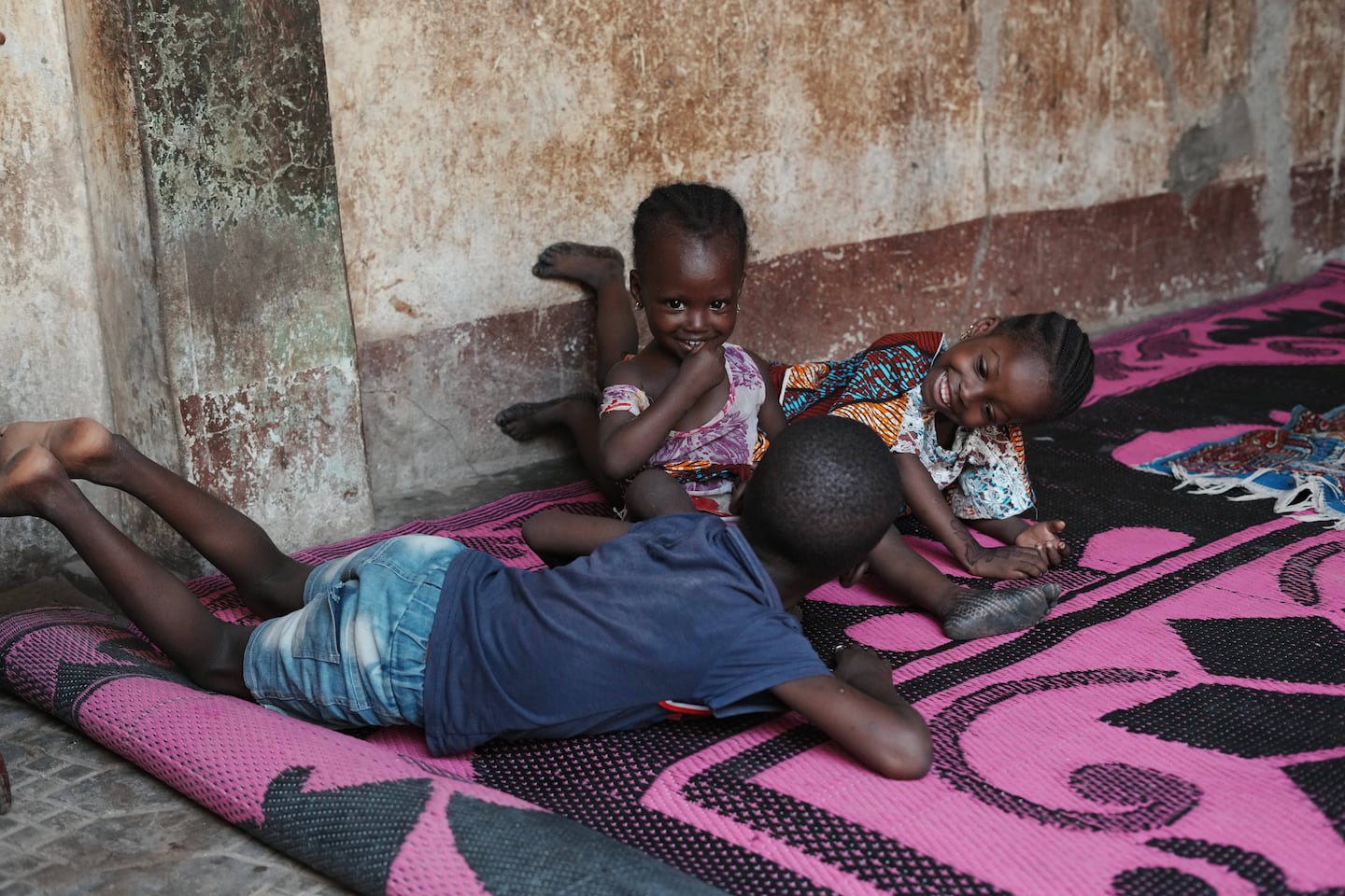Farisa, centre, who has relapsed into malnutrition, plays on a mat with her siblings inside her house in Kware Sokoto, northwestern Nigeria, on July 15, 2026.