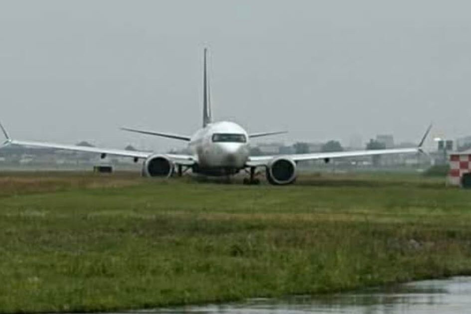 A passenger jet is seen in the grass at an airport.