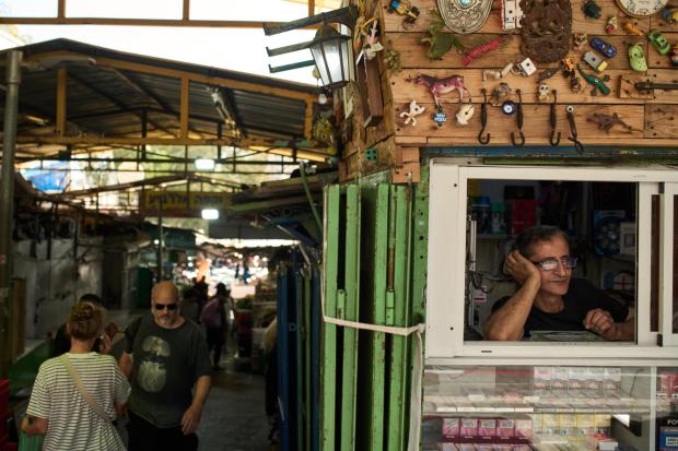 A vendor looks on from the window of his shop at a local street market.