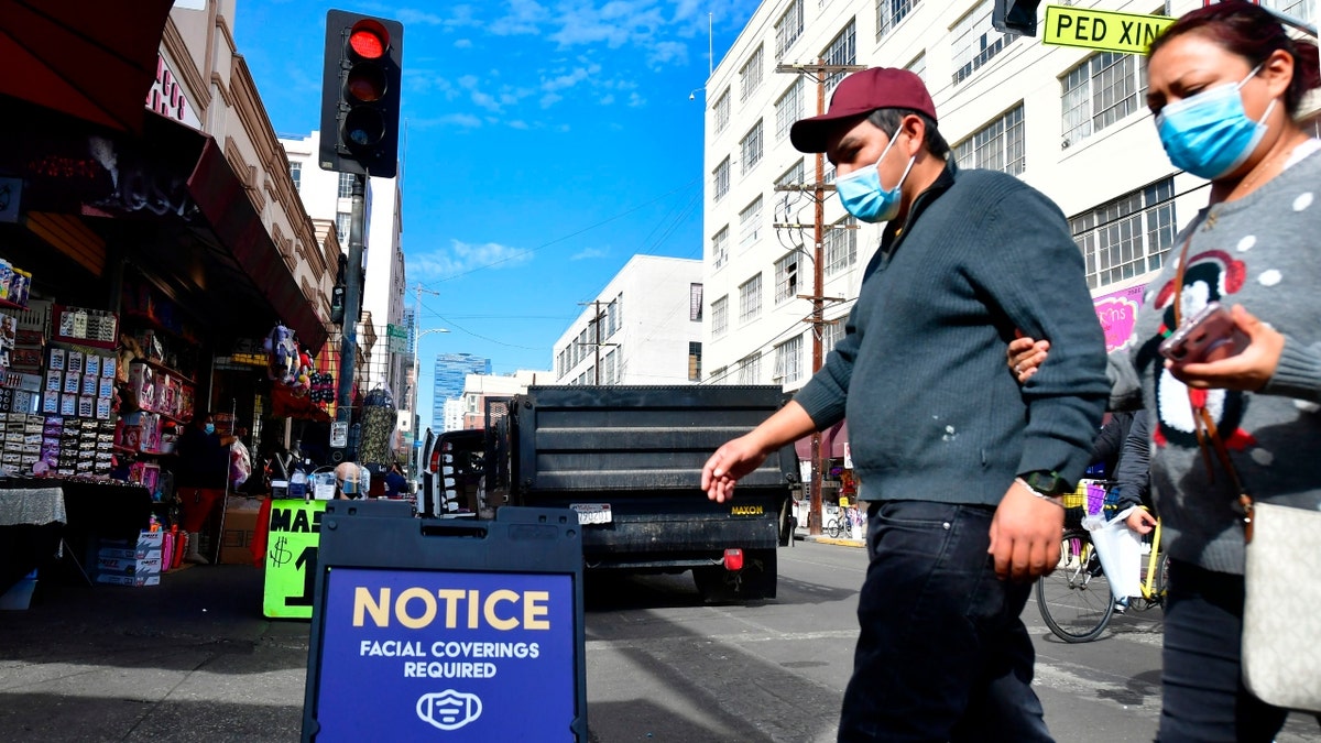 A signboard reminds people of a face covering requirement in Los Angeles