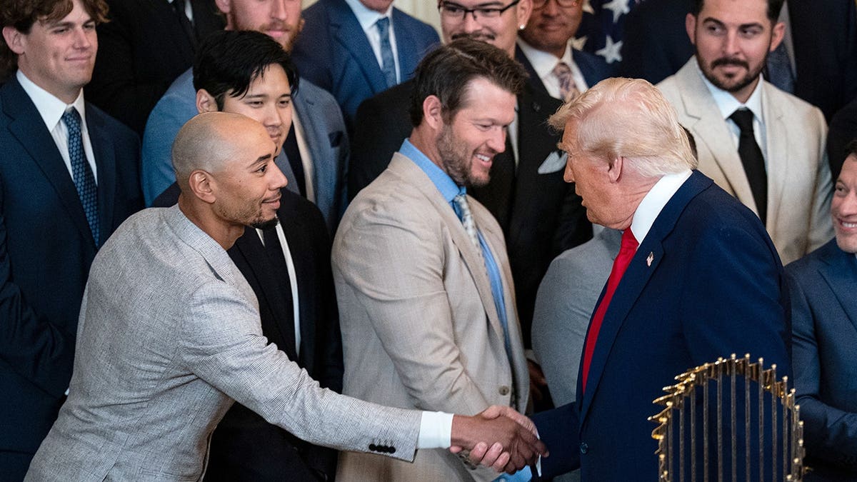 Donald Trump and Mookie Betts shake hands in the East Room of the White House.