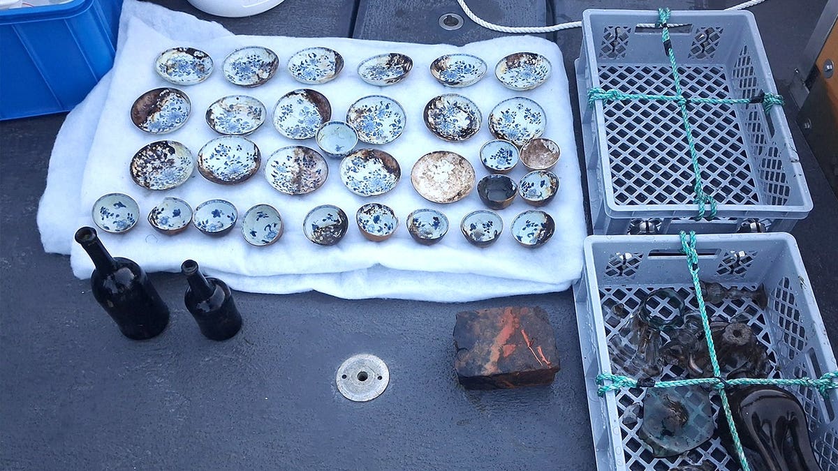 View of porcelain artifacts laid out next to other finds on ship