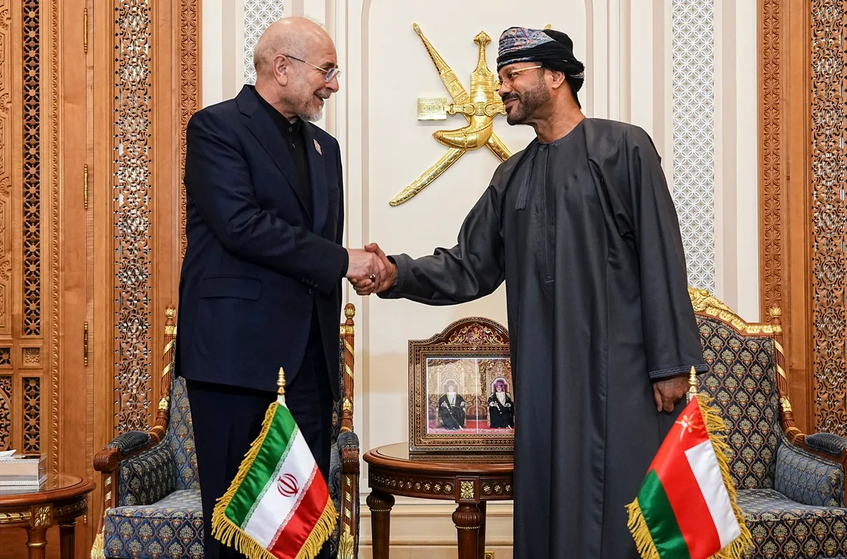 Iranian parliament speaker Mohammad Bagher Ghalibaf (L) shakes hands with Omani Foreign Minister Badr bin Hamad Al Busaidi in Muscat on June 22, 2026.