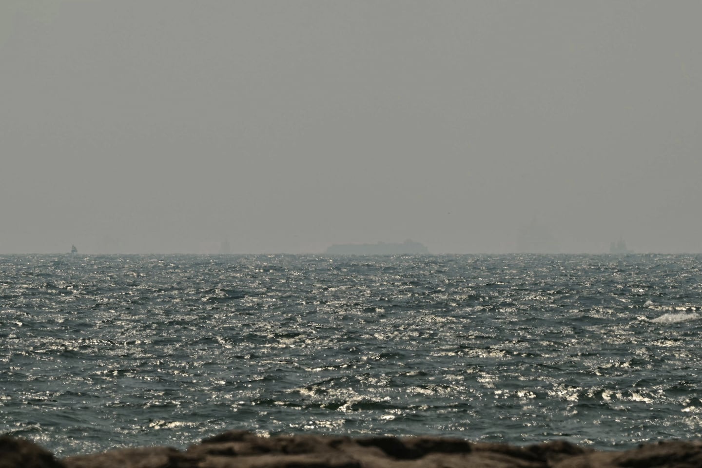 Ships are seen in the horizon as they sail off the coast of Ajman on July 10, 2026. Traffic through the Strait of Hormuz has fallen sharply since July 8, especially through the UN-backed Omani route, analysts said, after vessels were attacked earlier this week and as the United States and Iran traded renewed strikes.