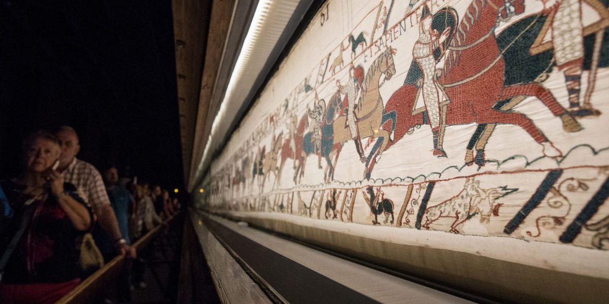 People look at the "Bayeux tapestry" or "Queen Mathilde tapestry" which relates Britain's conquest by William the Conqueror (Guillaume le Conquerant) in 1066, in Bayeux, western France, on September 13, 2019. (Photo by LOIC VENANCE / AFP) (Photo credit should read LOIC VENANCE/AFP via Getty Images)