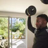 A man weight training at home in the living room - health and well being