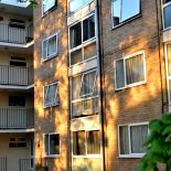 Numerous windows and balconies of a purpose built block of flats in nice dappled evening light in London