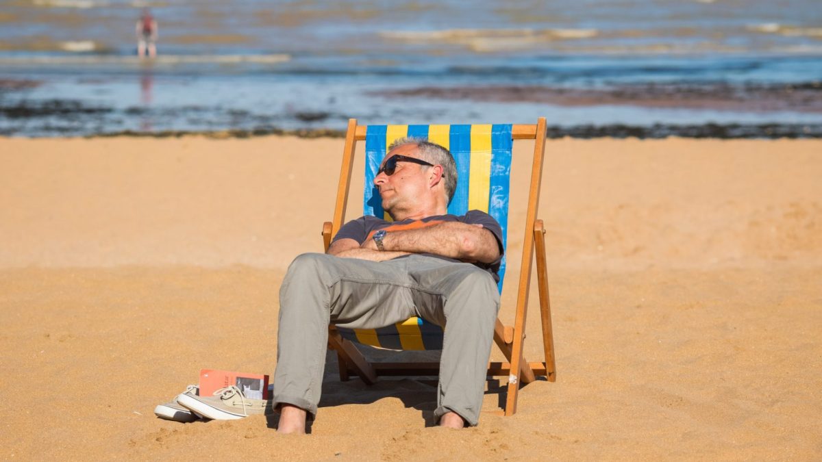 Kent, England - 14 June, 2022 - A man enjoying sunshine on a deck chair at Viking Bay in the seaside town of Broadstairs