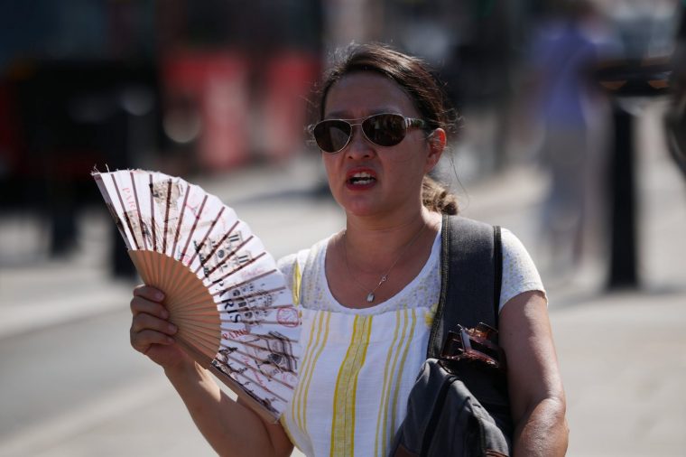 LONDON, ENGLAND - JUNE 26: A woman uses a fan to cool down on June 26, 2026 in London, England. On Thursday the temperature soared to 36.4C in Somerset, England, breaking the record for the hottest UK June temperature, set the day before. The Met Office has extended extreme heat warnings issued this week, with a red alert affecting parts of England extended until Friday, and amber warnings now in effect through Saturday. (Photo by Dan Kitwood/Getty Images)