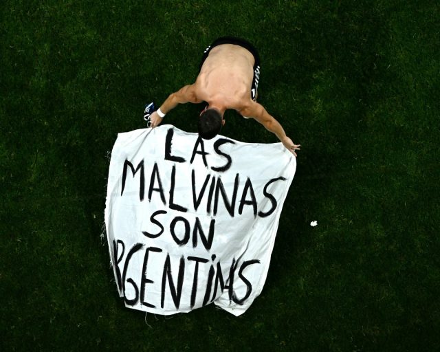 Argentina's midfielder #11 Giovani Lo Celso adjusts a banner reading "The Malvinas (Falkland Islands) belong to Argentina," after winning the 2026 World Cup football tournament semi-final match between England and Argentina at the Atlanta Stadium in Atlanta on July 15, 2026. (Photo by Jewel SAMAD / AFP via Getty Images)