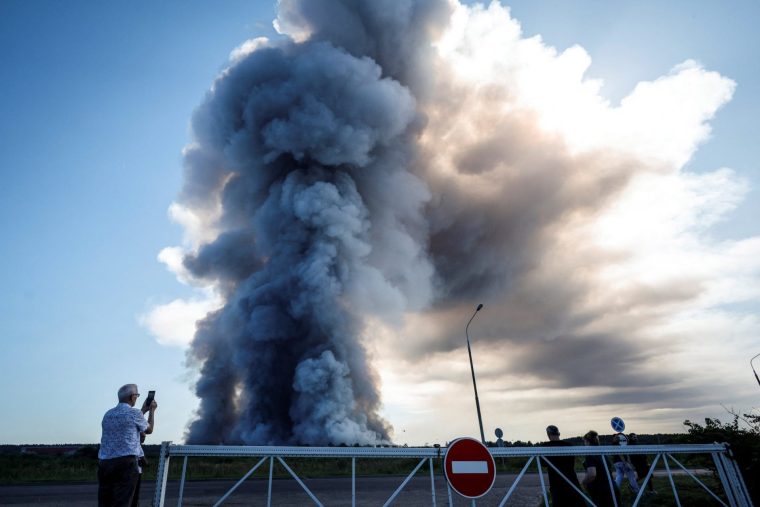 A local resident takes a picture of the smoke of a fire at the Russian e-commerce firm Wildberries' logistics complexes in the town of Elektrostal outside Moscow on July 18, 2026. A Ukrainian drone attack on two logistics centres in Russia killed eight people and injured 24, officials said on July 18, 2026, when the Moscow region reported a new wave of drone strikes. Russian e-commerce firm Wildberries said its logistics complexes in Kotovsk and Elektrostal, in the Tambov and Moscow regions respectively, came under attack. One person was killed and 37 were injured at the Elektrostal warehouse, according to the region's governor, Andrei Vorobyov. (Photo by TATYANA MAKEYEVA / AFP via Getty Images)