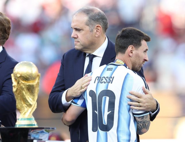 EAST RUTHERFORD, NEW JERSEY - JULY 19: Lionel Messi of Argentina looks dejected as he is embraced by Victor Montagliani, president of CONCACAF, while walking past the FIFA World Cup trophy after the FIFA World Cup 2026 Final match between Spain and Argentina at New York New Jersey Stadium on July 19, 2026 in East Rutherford, New Jersey. (Photo by Alex Livesey - Danehouse/Getty Images)