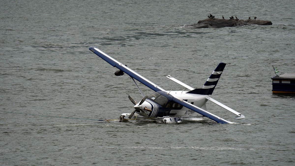 A seaplane sits partially submerged in New York City's East River after a hard landing