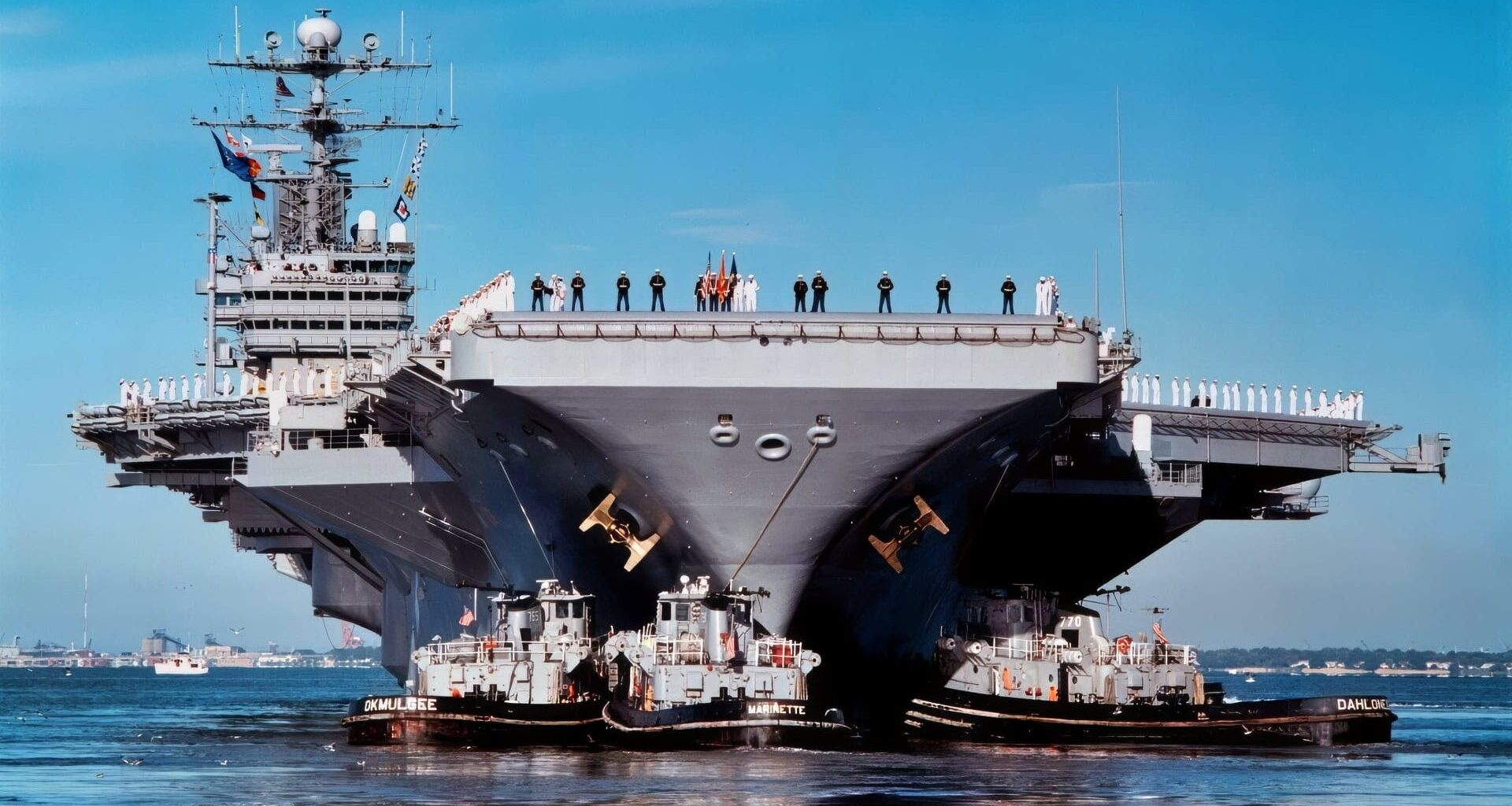 Sailors and Marines man the rail as three harbor tugs push the aircraft carrier USS George Washington (CVN 73) away from Pier 11 at Norfolk Naval Base on Oct. 3, 1997, for a scheduled six-month deployment. The George Washington will relieve the USS John F. Kennedy (CV 67) to conduct operations in the Mediterranean Sea.