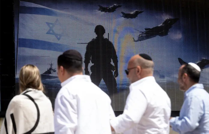 Israelis walk past a billboard saluting the Israeli pilots at Gordon Beach near the Mediterranean Sea, on the morning that U.S. and Iran agreed to a two-week conditional ceasefire in Tel Aviv, Israel on April 8. (Amir Levy/Getty Images)