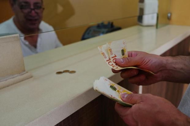 A customer counts Israeli Shekels at a currency exchange bureau in the West Bank.