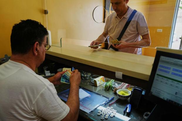 A currency exchange employee counts Israeli Shekels at a bureau in the West Bank.