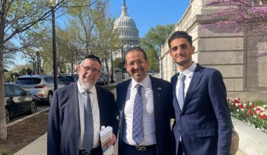 A photo of three men posing in from of the capitol building.