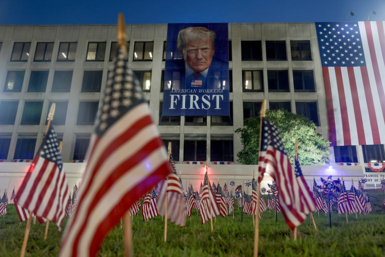 WASHINGTON, DC - JULY 03: American flags are planted in the ground in front of a banner of U.S. President Donald Trump, hanging from the U.S. Department of Labor building, ahead of July 4th festivities on July 03, 2026, in Washington, DC. A fireworks show will begin around 10:30 p.m on July 4th as the city deals with extreme heat warnings. Joe Raedle/Getty Images/AFP (Photo by JOE RAEDLE / GETTY IMAGES NORTH AMERICA / Getty Images via AFP)