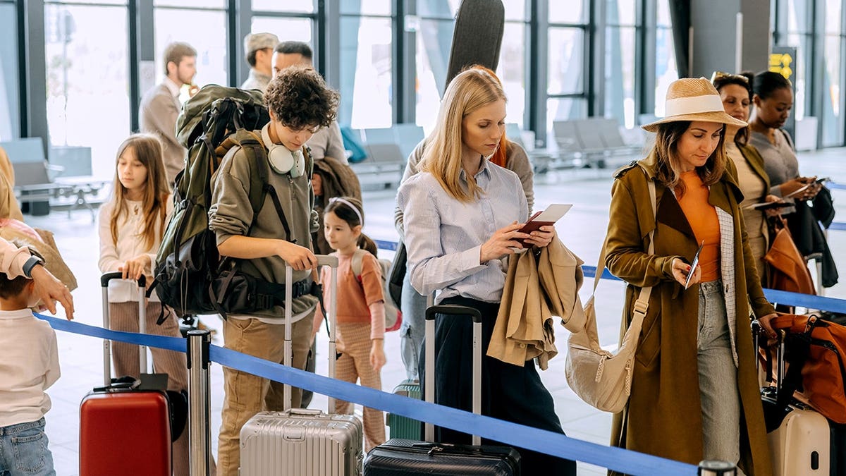 Passengers standing in line at an airport terminal with luggage