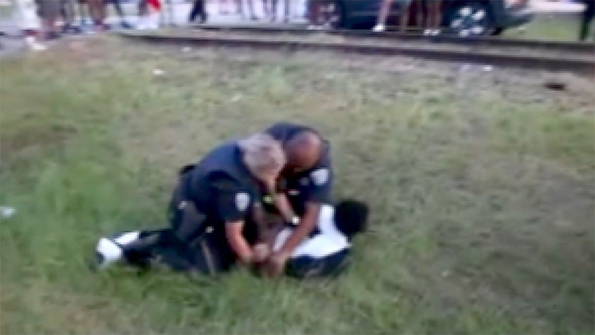 Two North Charleston police officers restrain a person on the ground during a Fourth of July block party that later erupted into violence