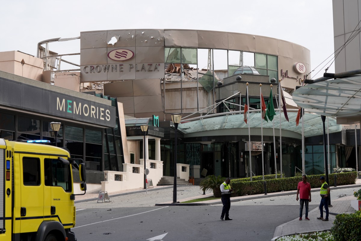 Security and civil defense workers stand outside the damaged Crown Plaza hotel, following an Iranian military strike, in Manama on March 1, 2026.
