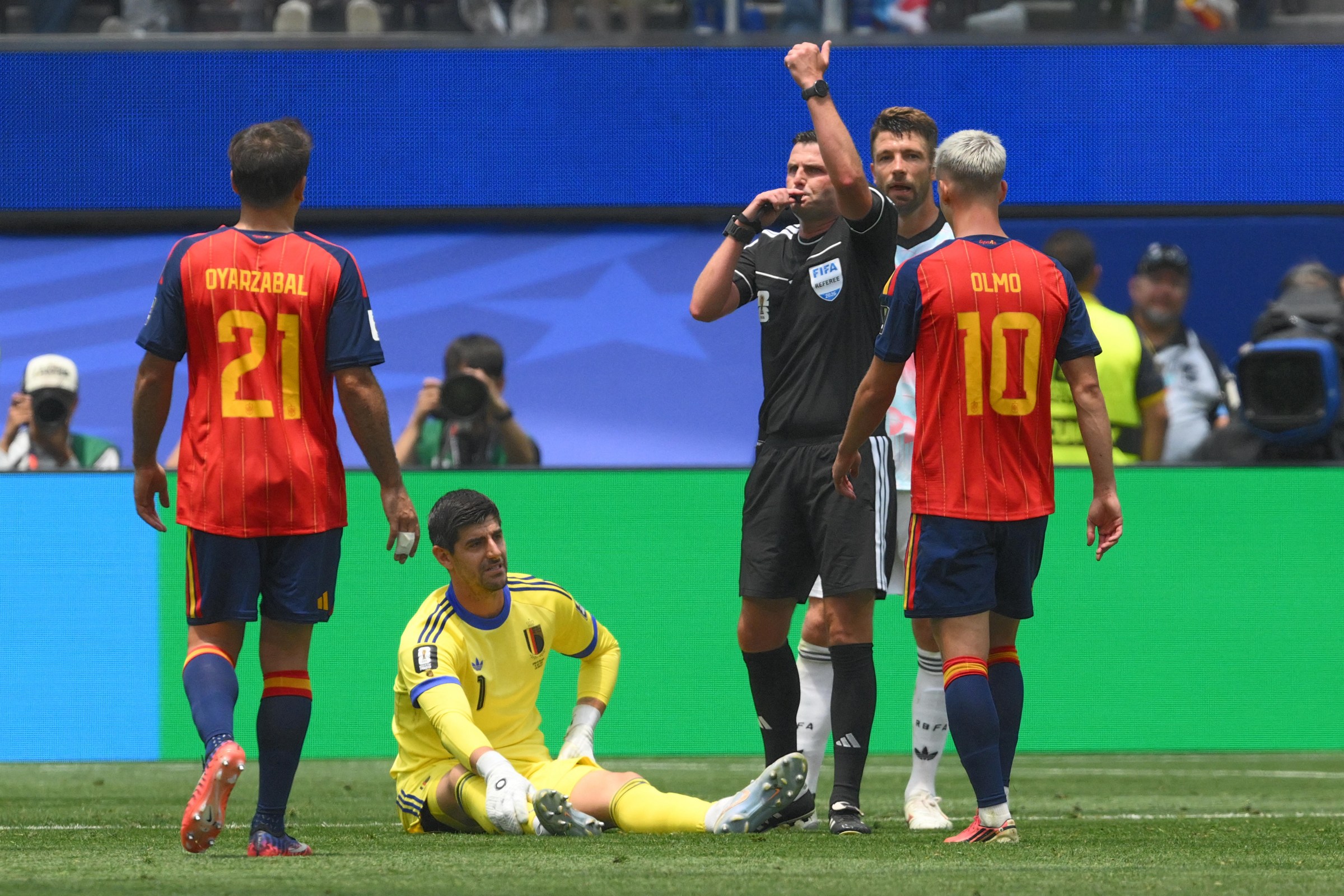 Belgium’s goalkeeper #01 Thibaut Courtois sits on the field past English referee Michael Oliver during the 2026 World Cup football tournament quarter-final match between Spain and Belgium at the Los Angeles Stadium in Inglewood on July 10, 2026. (Photo by Patrick T. Fallon / AFP via Getty Images)