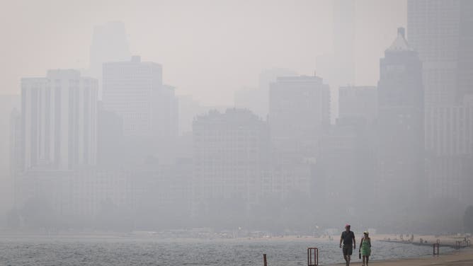 CHICAGO, ILLINOIS - JULY 16: A couple walks along Lake Michigan as smoke from Canadian wildfires blankets the city on July 16, 2026 in Chicago, Illinois. City officials have encouraged people to stay inside as the air quality index today in the city has been rated "very unhealthy", with some nearby suburban areas rated "hazardous".