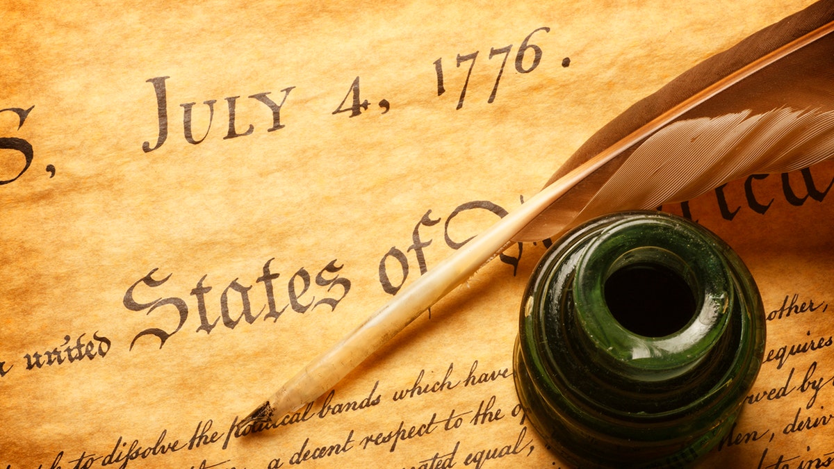A feather quill and inkwell resting on the American Declaration of Independence document.