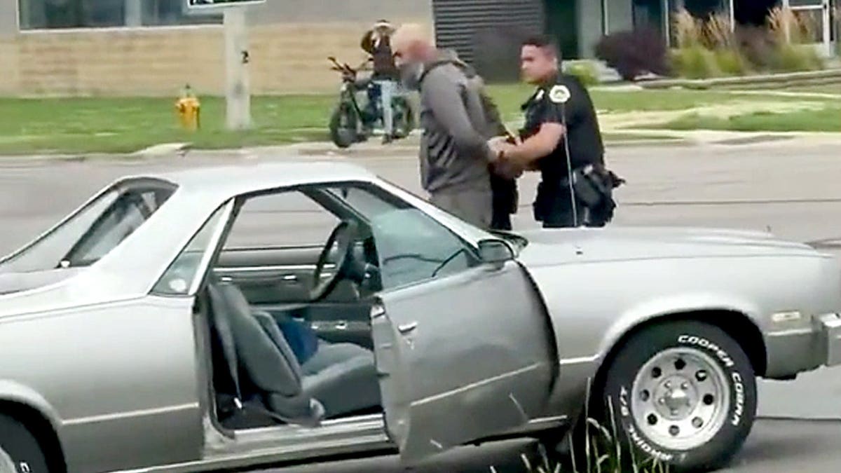 A Des Moines police officer escorts a handcuffed man away from the scene of a road rage incident.