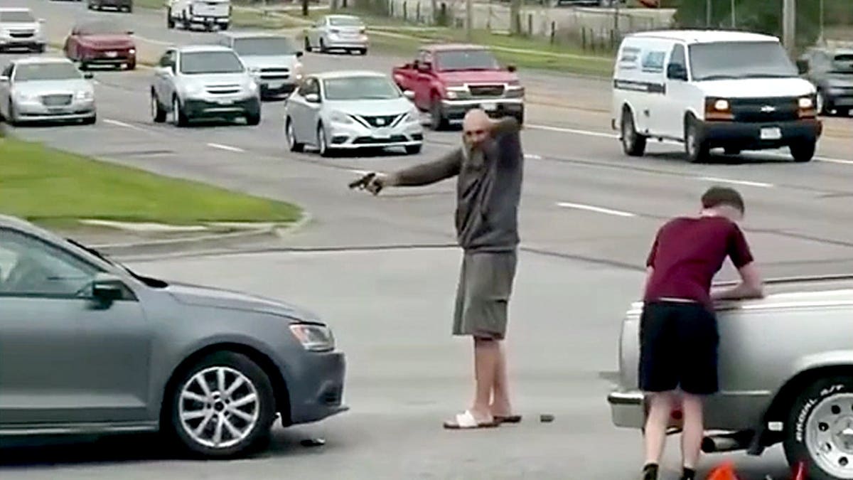 A man points a handgun toward the occupants of a gray sedan after a crash in Des Moines, Iowa.