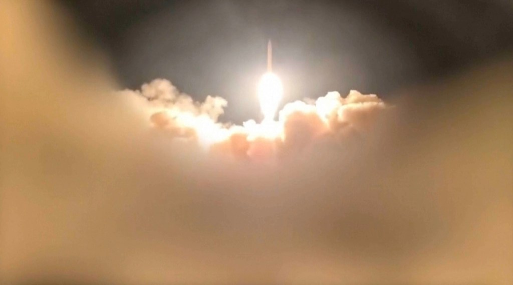 A bright missile soaring through a night sky, leaving a trail of smoke and light.