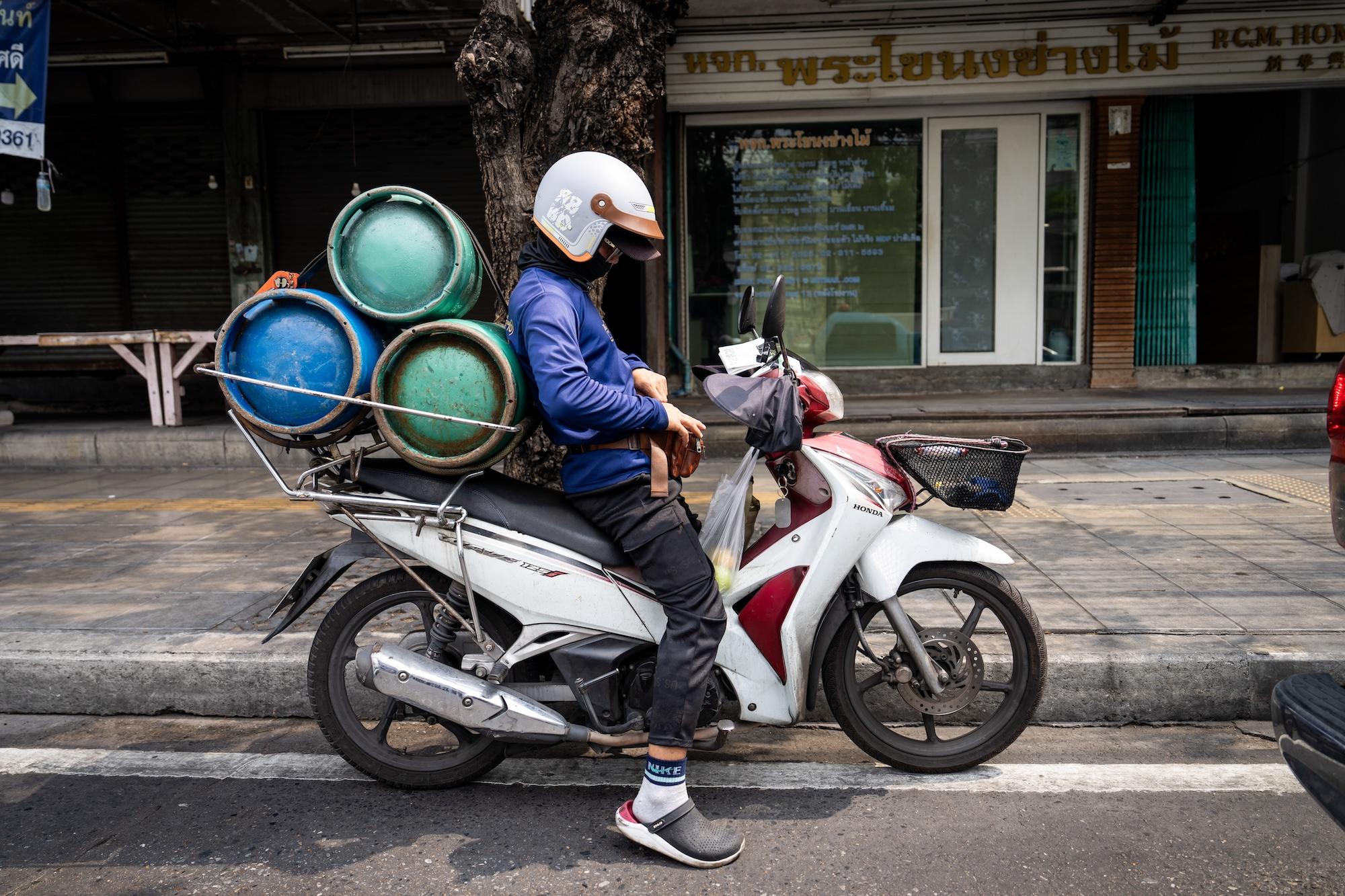 A man on a motorcycle carrying gas cylinders