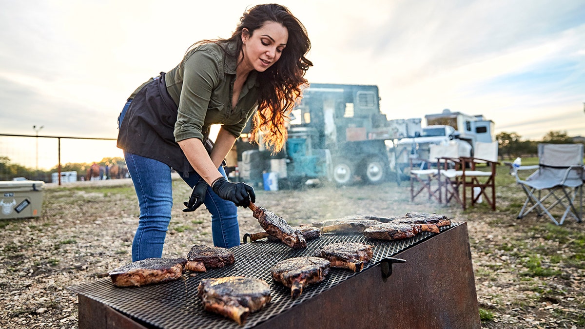 Jess Pryles hands meat on the grill.