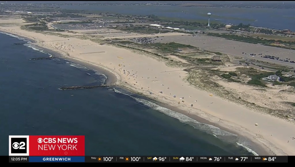 Aerial view of Point Lookout Beach on Long Island with numerous beachgoers, parking lots, and coastal buildings.