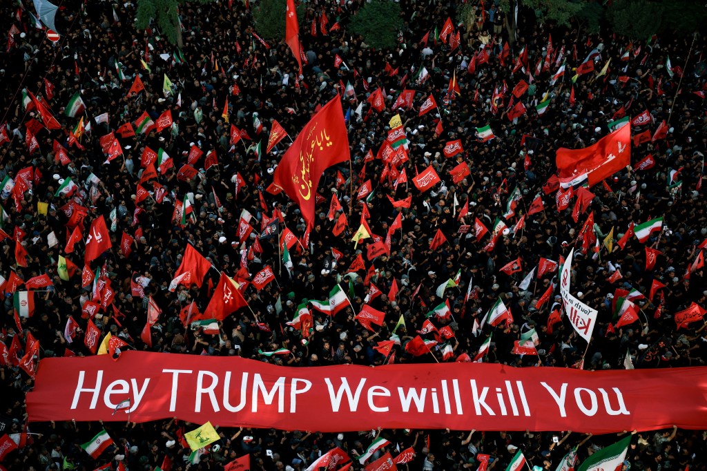Mourners at the burial of Iran's late Supreme Leader Ayatollah Ali Khamenei carry a banner that reads "Hey TRUMP We will kill You".