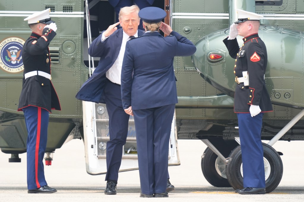 Donald Trump salutes with two service members by Marine One.