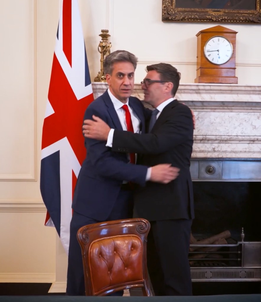 Prime Minister Andy Burnham shakes hands with Ed Miliband.