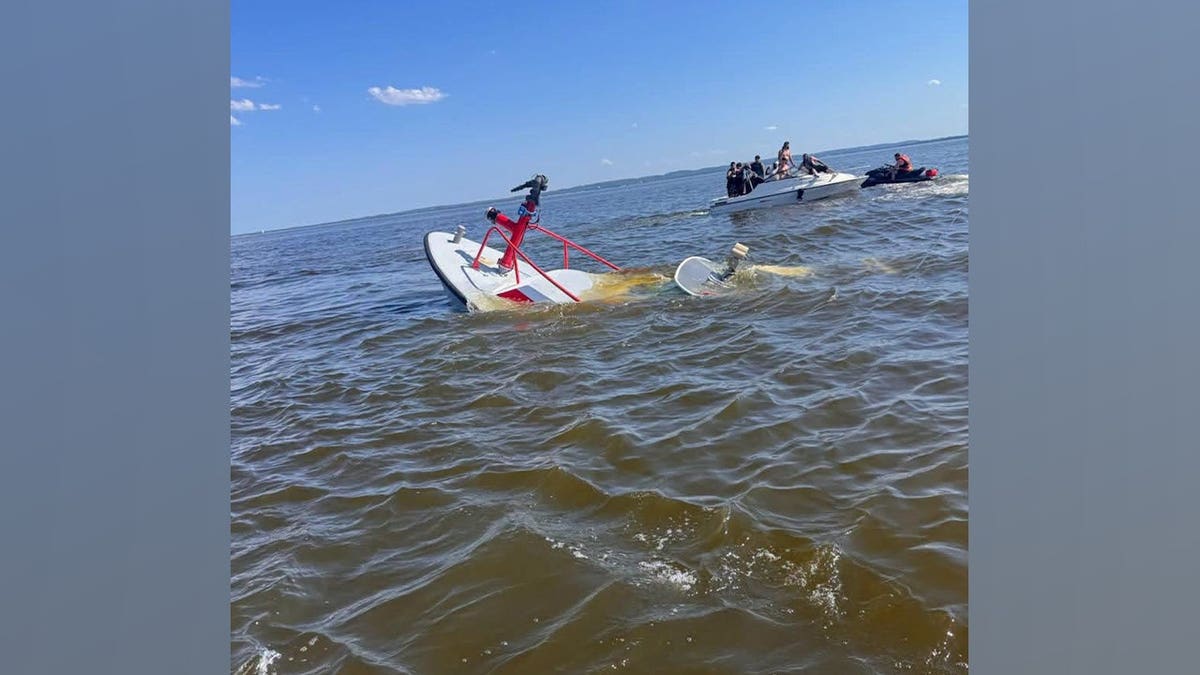 Damaged Carteret Fire Department rescue boat partially submerged in Raritan Bay as nearby boaters assist.